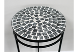 Round side table with black and white mosaic tile top and black metal legs, angled view against white wall.