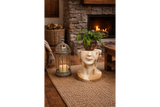 Cream and gold distressed ceramic Head Side Table shaped like a face, angled with a plant on top in cozy room setting.