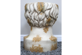 Round head-shaped side table in distressed white and gold finish, shown from rear on grey carpet.