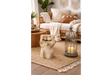 Beige stone fist-shaped side table in a cozy living room setting with wicker sofa and candle lantern.