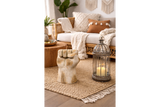 Beige stone fist-shaped side table in a cozy living room setting with wicker sofa and candle lantern.