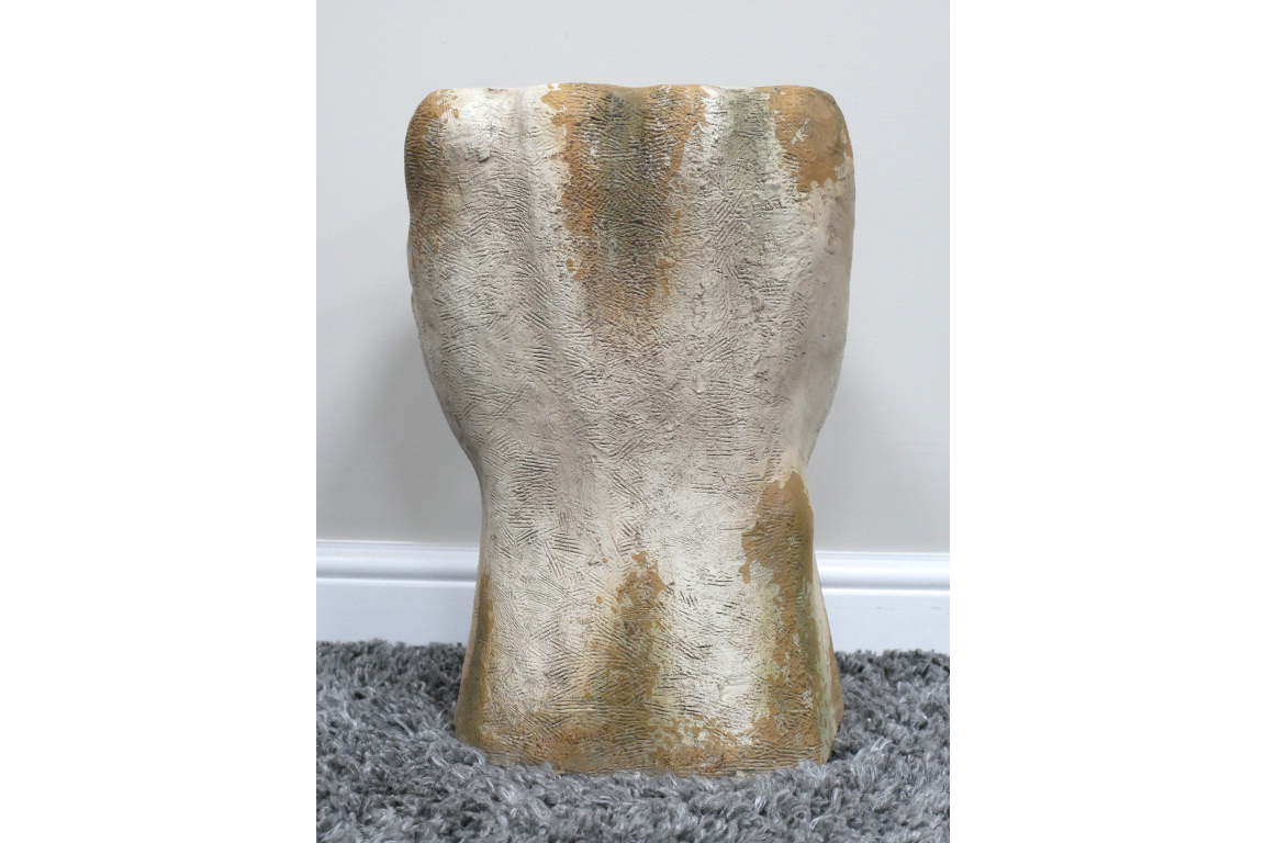 Abstract sculptural side table in textured gold and silver metallic finish, shown from the front on a gray rug.