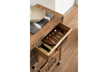 Wooden wine cabinet drawer open showing four metal spoons and two cans of soda, angled top view.