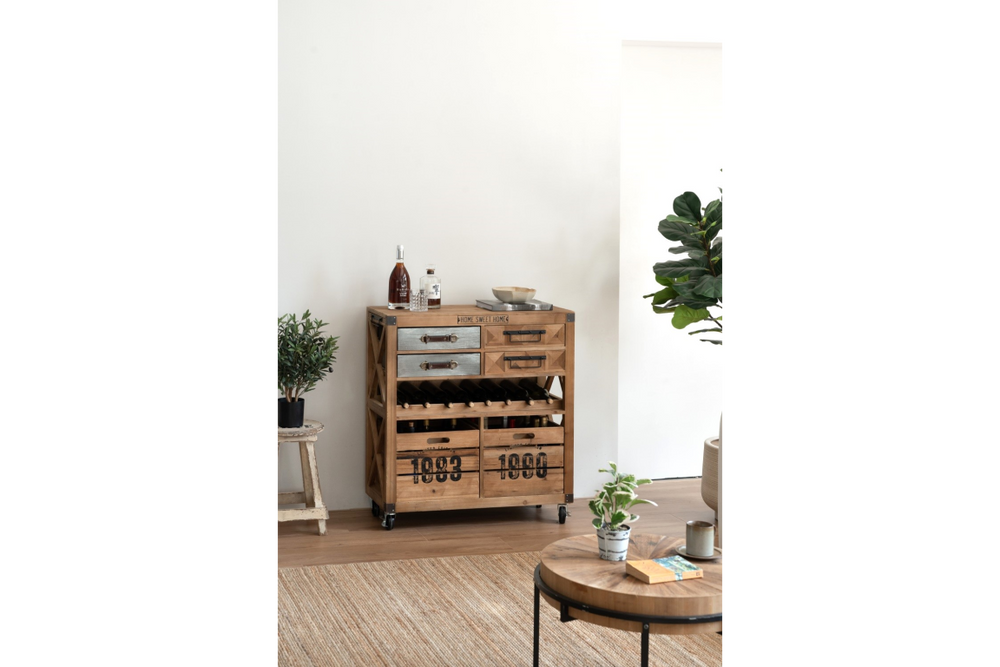 Wooden wine cabinet with metal drawers, bottle storage, and wheels, shown in a living room setting from front angle.