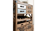 Wood and metal wine cabinet with four drawers, two wooden crates, and horizontal bottle storage, angled side view.