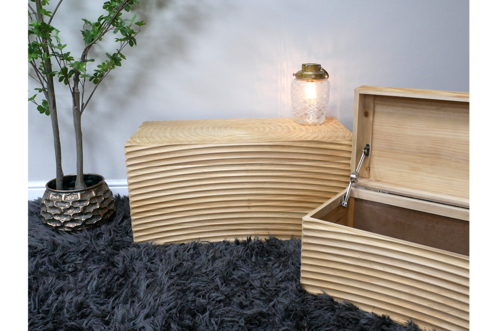 Set of two light wood storage boxes with carved horizontal grooves, one open, shown on black shaggy rug with potted plant.