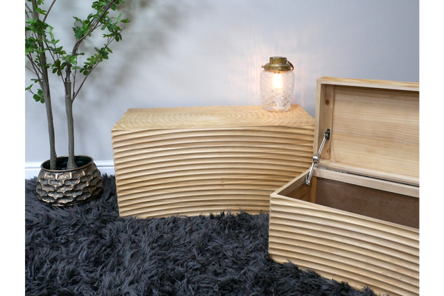 Set of two light wood storage boxes with carved horizontal grooves, one open, shown on black shaggy rug with potted plant.