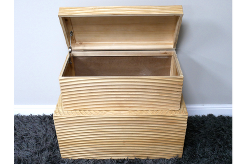 Set of two light wood storage boxes with horizontal grooves, one open showing interior, placed on dark grey carpet.