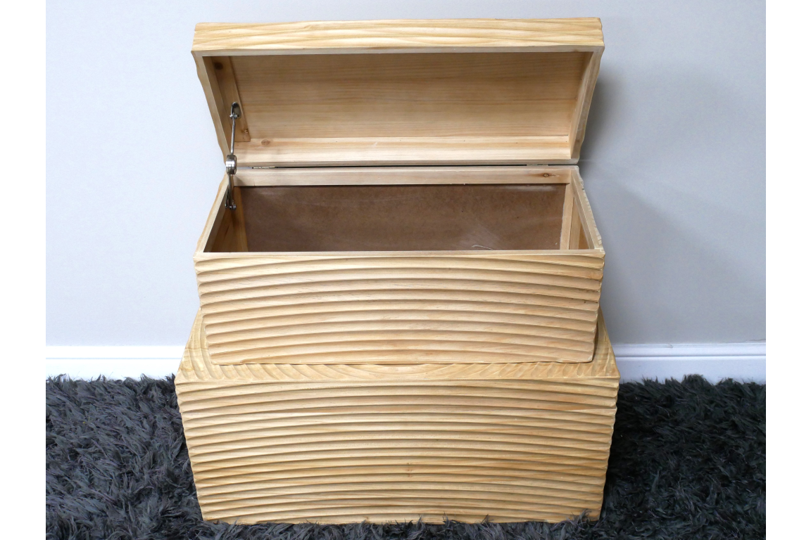 Set of two light wood storage boxes with horizontal grooves, one open showing interior, placed on dark grey carpet.