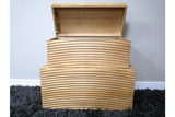 Set of two light wood storage boxes with carved wave patterns, one open, stacked on dark grey shag carpet.