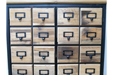 Storage cabinet with sixteen small wooden drawers featuring black metal handles and label holders, front view.