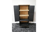 Black metal storage cabinet with light wood shelves, open doors, standing on gray carpet against white wall.