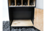 Black metal and light wood wine cabinet with four wine slots, open door, shown from front on dark rug.