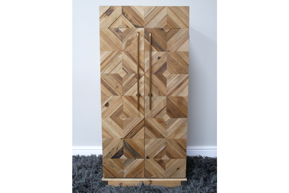 Wooden wine cabinet with geometric square pattern front, vertical metal handles, standing on gray shaggy rug.