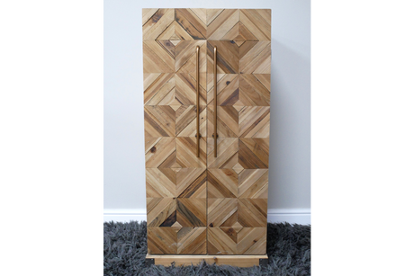 Wooden wine cabinet with geometric square pattern front, vertical metal handles, standing on gray shaggy rug.