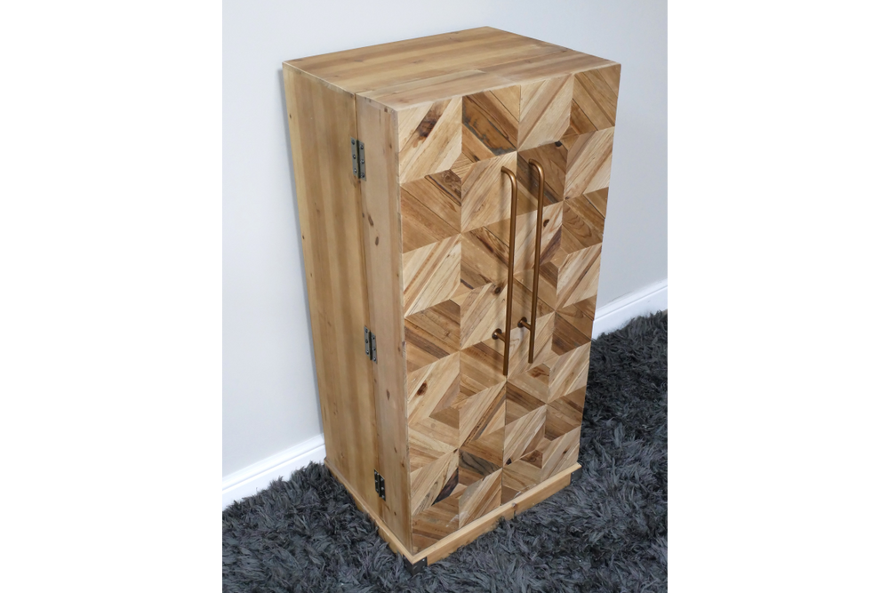 Wooden wine cabinet with geometric patterned front, bronze handles, viewed from a side angle on grey carpet.