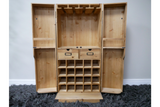Light wood wine cabinet with open double doors, row of bottle slots, two drawers, and hanging rack, front view.