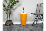 Round yellow side table with white top, ceramic material, shown with bottle on top, next to black wire chair and potted