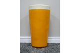 Lager Side Table shaped like a yellow and white pint glass, ceramic material, front view on grey carpet against white wall.