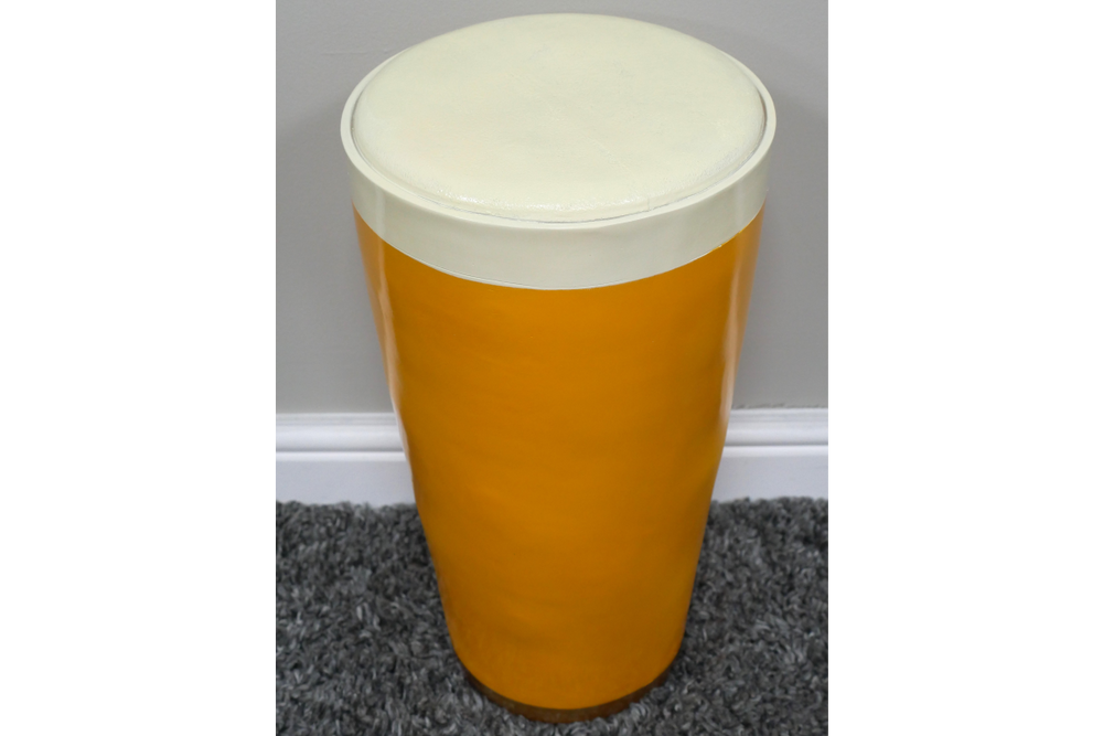 Cylindrical Lager Side Table with glossy yellow base and white round cushioned top, shown from above on gray carpet.