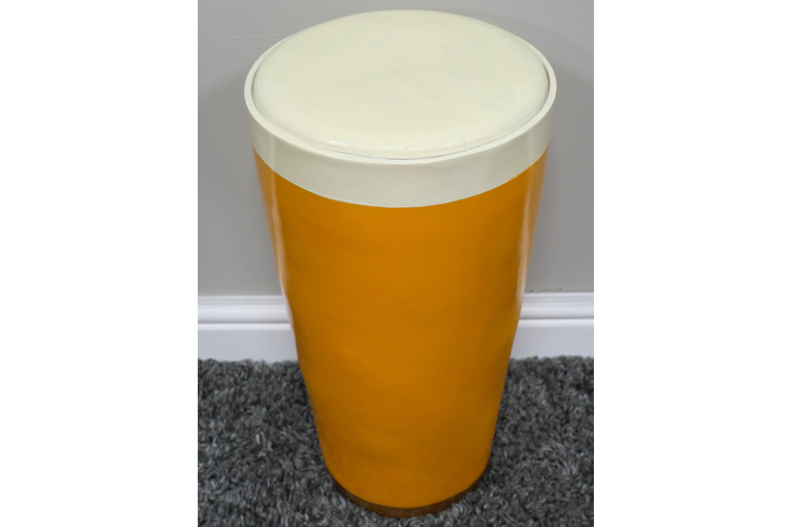 Cylindrical Lager Side Table with glossy yellow base and white round cushioned top, shown from above on gray carpet.