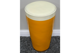 Cylindrical Lager Side Table with glossy yellow base and white round cushioned top, shown from above on gray carpet.