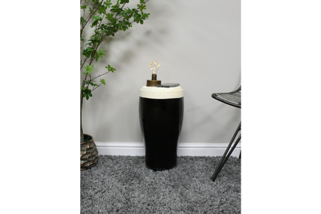 Black and white ceramic stout side table with lamp and smartphone on top, shown in a carpeted room corner from front angle.