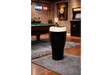 Black and white ceramic stout pint-shaped side table with lamp and smartphone in a game room setting.