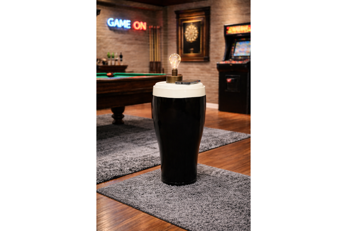 Black and white ceramic stout pint-shaped side table with lamp and smartphone in a game room setting.