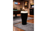 Black and white ceramic stout pint-shaped side table with lamp and smartphone in a game room setting.