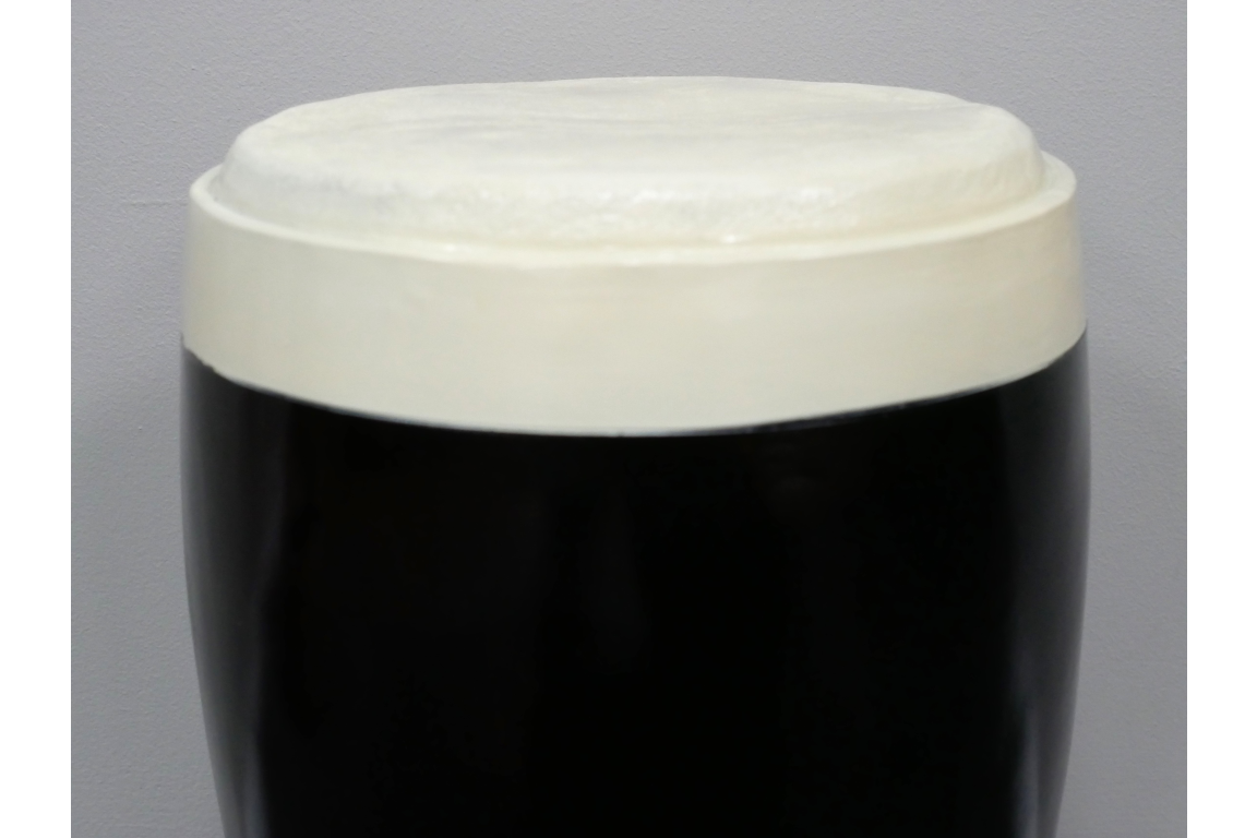 Round stout side table with black glossy base and off-white textured top, shown from a front angle on a gray background.