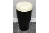 Black and white ceramic stout side table with rounded top, cylindrical shape, shown on gray carpet against beige wall.