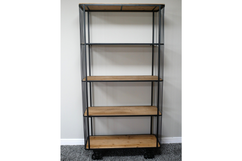 Tall shelving unit with natural wood shelves and black metal frame on wheels, standing on grey carpet.