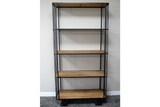 Tall shelving unit with natural wood shelves and black metal frame on wheels, standing on grey carpet.