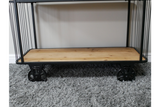 Black metal frame shelves with light wood base and industrial style black wheels on grey carpet floor.