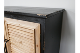 Shutter bar cabinet with distressed black wood frame and natural unfinished wooden louvered door, side angle view.