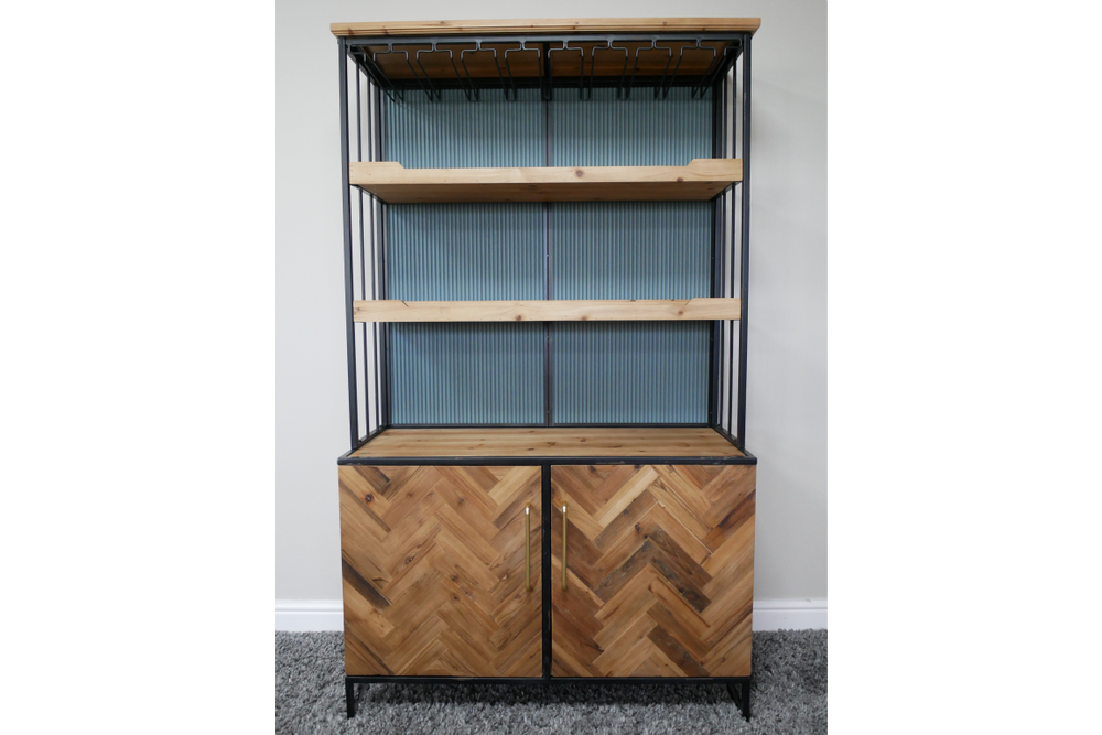 Bar cabinet with light wood shelves, herringbone wood doors, black metal frame, angled front view on grey carpet