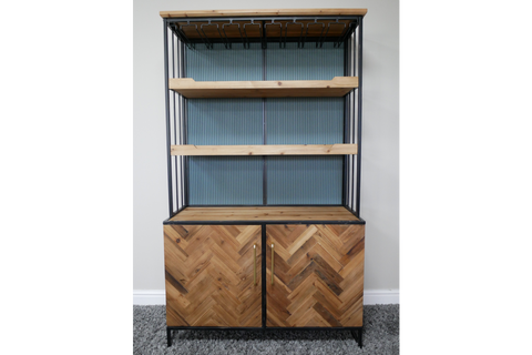 Bar cabinet with light wood shelves, herringbone wood doors, black metal frame, angled front view on grey carpet
