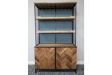 Bar cabinet with light wood shelves, herringbone wood doors, black metal frame, angled front view on grey carpet