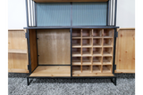 Wooden bar cabinet with black metal frame, open doors, divided bottle storage, and shelving on gray carpet.