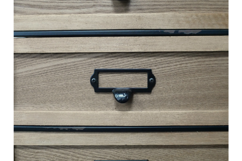 Close-up of light brown wooden industrial drawer cabinet with black metal handle and label holder.