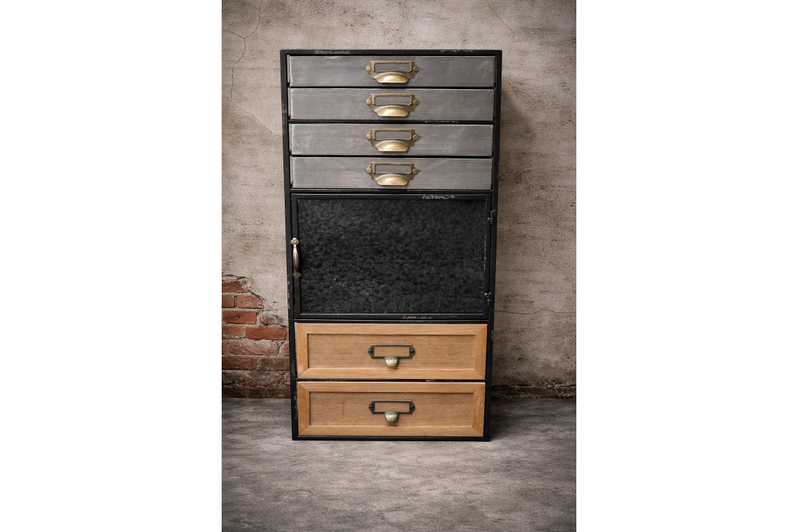 Tall industrial drawer cabinet with mixed metal and wood drawers, black frame, brass handles, front view against textured