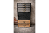 Tall industrial drawer cabinet with mixed metal and wood drawers, black frame, brass handles, front view against textured