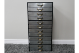 Tall industrial drawer cabinet with ten metal drawers and brass handles, front view on gray carpet.
