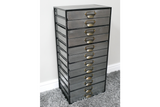 Tall industrial drawer cabinet with ten gray metal drawers and brass handles, side angled view on carpeted floor.