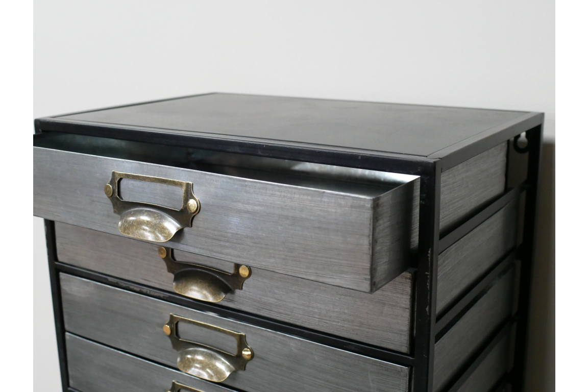 Metal industrial drawer cabinet with five drawers, brass handles, shown from front angle with one drawer open.