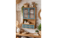 Wooden Parisienne wall unit with blue cabinet doors and drawers, glass panels with white text, staged with plants and decor.