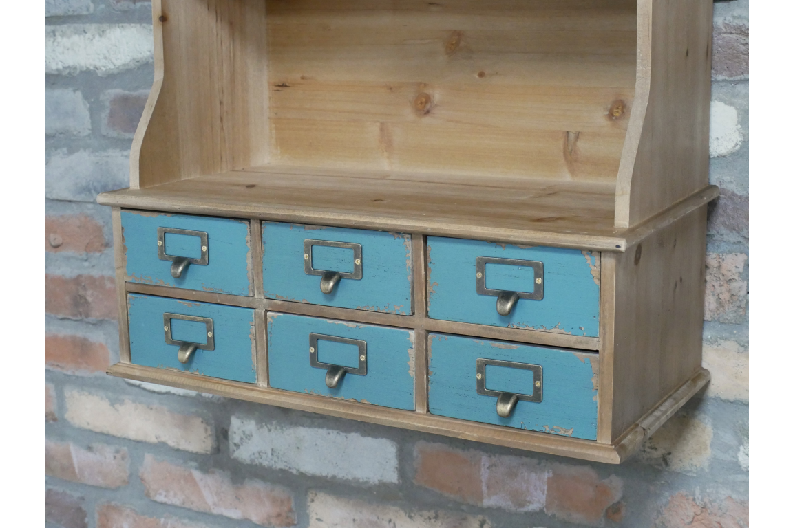 Wooden wall unit with six distressed blue drawers and metal handles, shown at an angle against a brick wall.