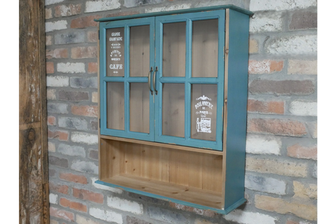 Blue wooden wall unit with two glass paneled doors and open shelf below, mounted on a brick wall, side angle view.