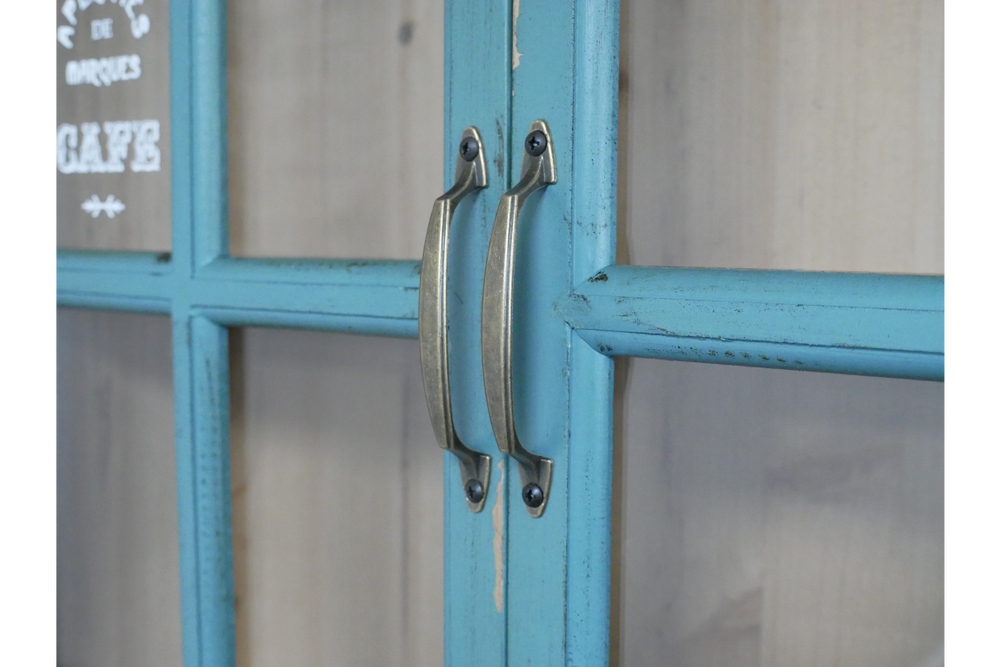 Close-up of blue painted wooden wall unit doors with metal handles and glass panels.